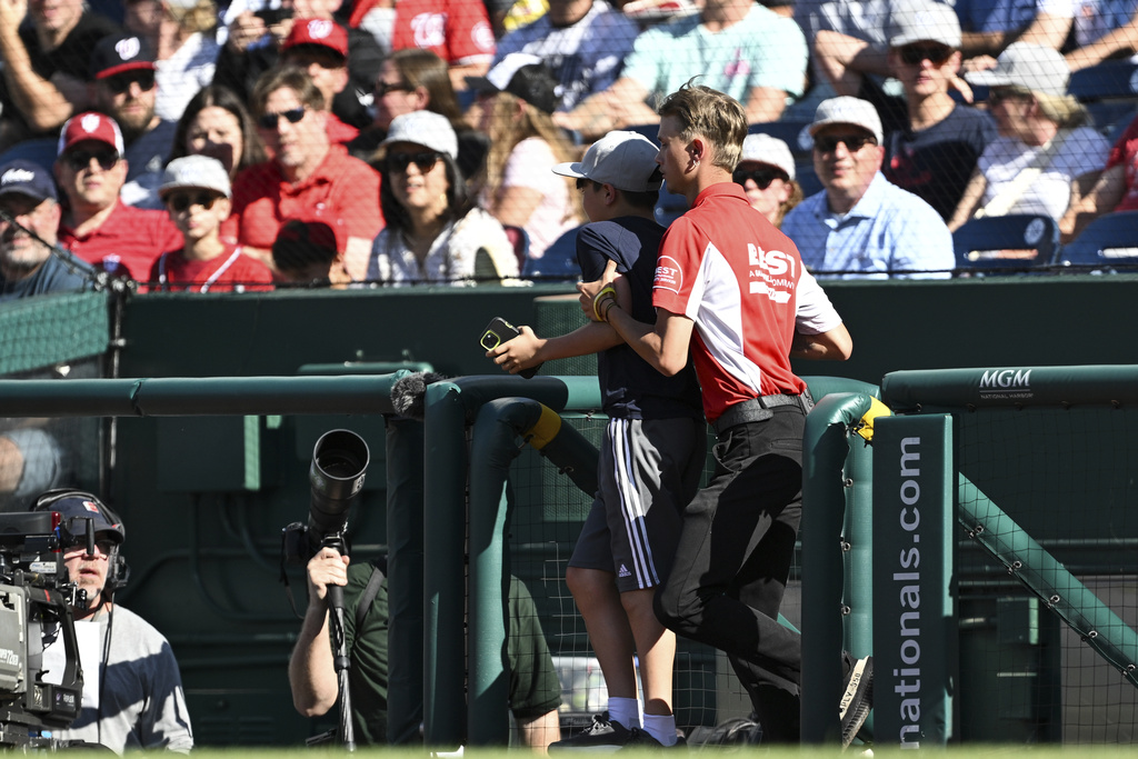 A young fan is ushered off the field during the third inning of a baseball game between the Washington Nationals and the Tampa Bay Rays, Saturday, Aug. 30, 2025, in Washington. (AP Photo/Terrance Williams)