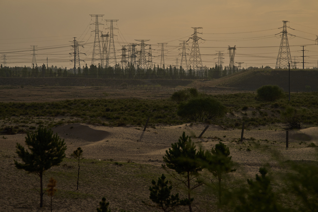 Electric pylons are seen in the horizon along sand dunes near Ordos in northern China's Inner Mongolia province on Thursday, June 11, 2026. (AP Photo/Ng Han Guan)