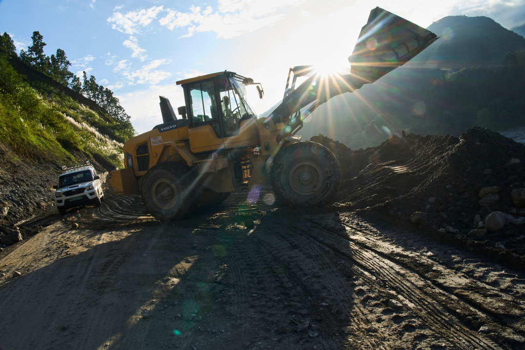 An excavator cuts into a hillside to build a temporary road connecting towns and villages after flash floods destroyed the existing road in Nepal's Nuwakot district, Tuesday, Sept. 22, 2026. (AP Photo/Niranjan Shrestha)