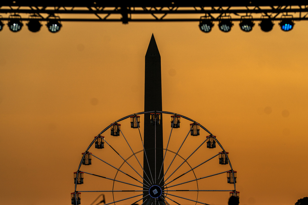The Washington Monument and the ferris wheel on the National Mall are seen at sunset, Wednesday, July 1, 2026, on the National Mall in Washington. (AP Photo/Allison Robbert)