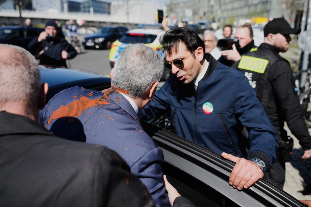 Iran's Reza Pahlavi, exiled son of Shah Reza Pahlavi, is protected by security after he was attacked with a red fluid, following a news conference in Berlin, Germany, Thursday, April 23, 2026. (AP Photo/Markus Schreiber)