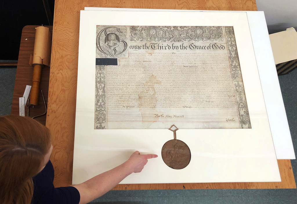 FILE - Rhode Island state archivist Ashley Selima points to the seal of King George III on a September 1772 proclamation in Providence, R.I., May 24, 2018. (AP Photo/Jennifer McDermott, File)