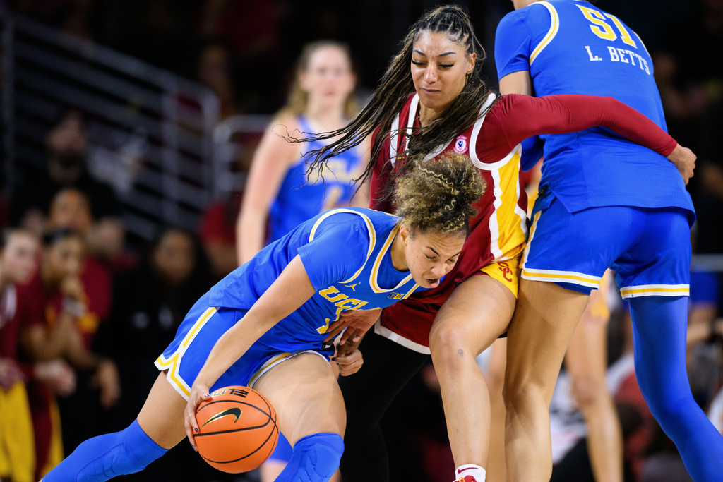 UCLA guard Kiki Rice, left, drives the ball against Southern California guard Kennedy Smith, center, during the first half of an NCAA college basketball game Sunday, March 1, 2026, in Los Angeles. (AP Photo/William Liang)