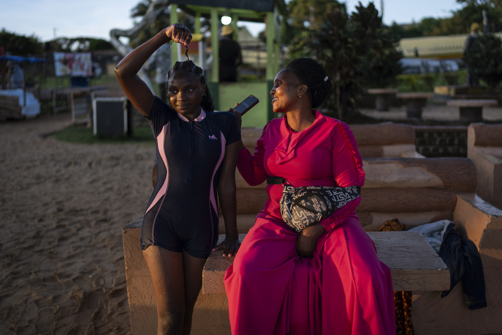Janet Nampija, right, looks at her daughter Nakaima Hairat, 14, after a swim in Lake Victoria as they sit along a beach at sunset Monday, Nov. 25, 2024, in Entebbe, Uganda, home to one of the world's youngest populations. (AP Photo/David Goldman)