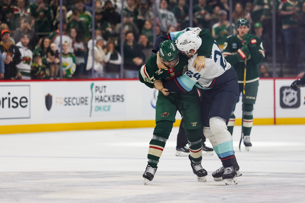 Minnesota Wild's Marcus Foligno (17) and Seattle Kraken's Jamie Oleksiak (24) fight during the first period of an NHL hockey game Tuesday, April 7, 2026, in St. Paul, Minn. (AP Photo/Lily Dozier)