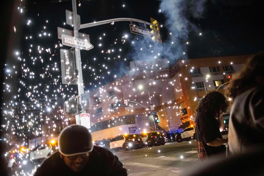 People take cover as a fireworks explosion occurs during a protest near the Metropolitan Detention Center in downtown Los Angeles, June 8, 2025. (AP Photo/Ethan Swope, File)