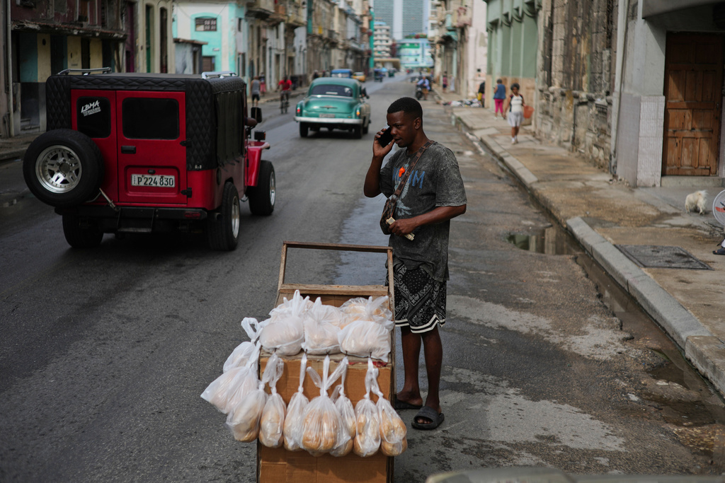 A bread vendor holds a cell phone up to his ear during irregular connectivity due to a blackout in Havana, Tuesday, March 17, 2026. (AP Photo/Ramon Espinosa)