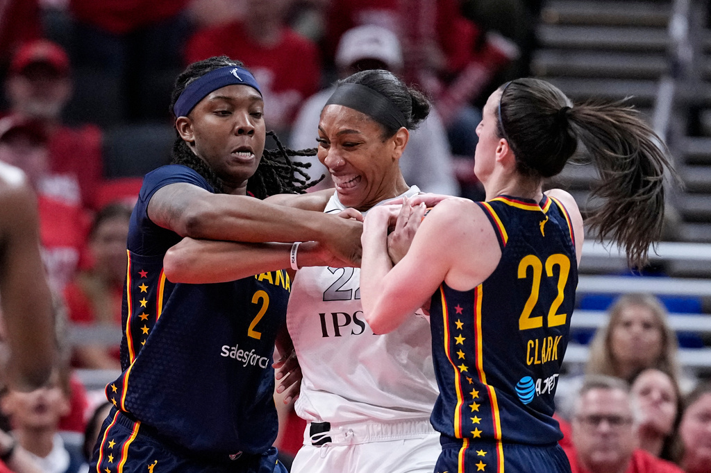 Indiana Fever guard Caitlin Clark (22) and forward Myisha Hines-Allen (2) tie up Las Vegas Aces center A'ja Wilson, center, during the first half in Game 2 of a WNBA basketball first-round playoff series in Indianapolis, Tuesday, Sept. 29, 2026. (AP Photo/Michael Conroy)