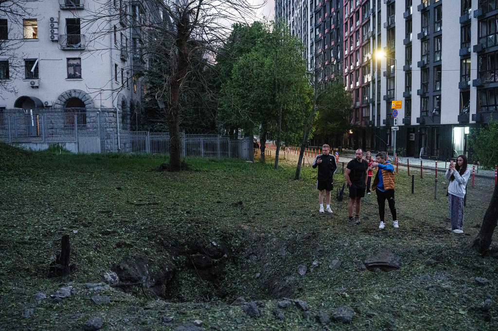FILE - People stand by a crater from a Russian missile strike in the Lukianivka neighbourhood of Kyiv, Ukraine, May 24, 2026. (AP Photo/Evgeniy Maloletka)
