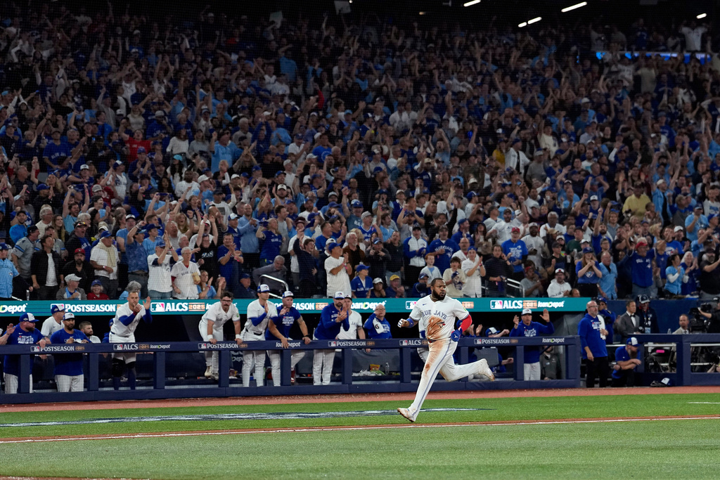 Toronto Blue Jays' Vladimir Guerrero Jr. scores on after throwing error during the seventh inning in Game 6 of baseball's American League Championship Series against the Seattle Mariners, Sunday, Oct. 19, 2025, in Toronto. (AP Photo/David J. Phillip)