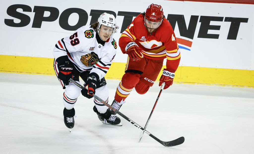 Chicago Blackhawks' Tyler Bertuzzi, left, checks Calgary Flames' Rasmus Andersson, right, during third-period NHL hockey game action in Calgary, Alberta, Friday, Nov. 7, 2025. (Jeff McIntosh/The Canadian Press via AP)