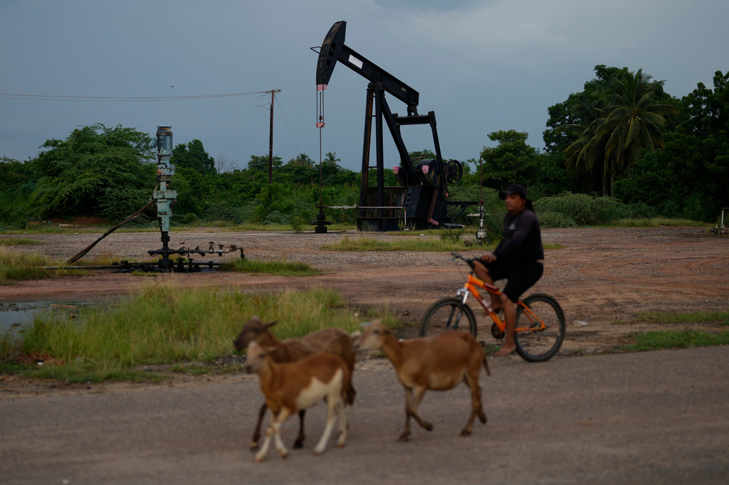 A man rides past an operating oil pumpjack in Cabimas, Venezuela, Monday, Aug. 31, 2026. (AP Photo/Ariana Cubillos)