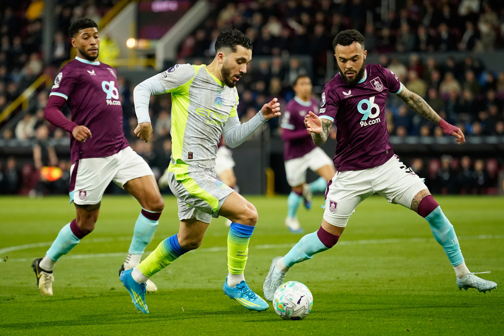 Manchester City's Rayan Cherki in action between Burnley's Josh Laurent, left, and Quilindschy Hartman during the Premier League soccer match between Burnley and Manchester City in Burnley, England, Wednesday, April 22, 2026. (AP Photo/Dave Thompson)