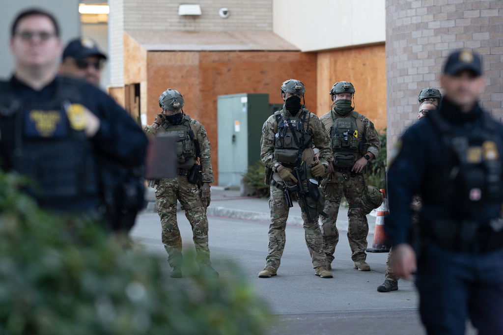 FILE - Law enforcement officers look out from a United States Immigration and Customs Enforcement (ICE) facility Oct. 21, 2025, in Portland, Ore. (AP Photo/Jenny Kane, File)