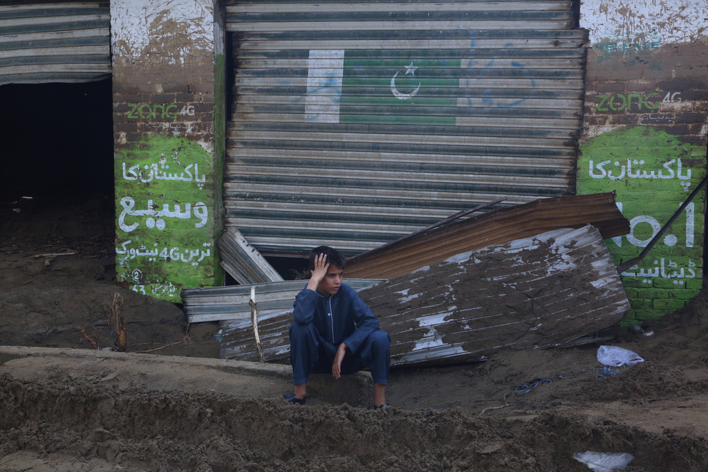 A boy sits in front of shops damaged by Friday's flash flooding on the outskirts of Pir Baba, Buner district, in Pakistan's northwest, Saturday, Aug. 16, 2025. (AP Photo/Muhammad Sajjad)