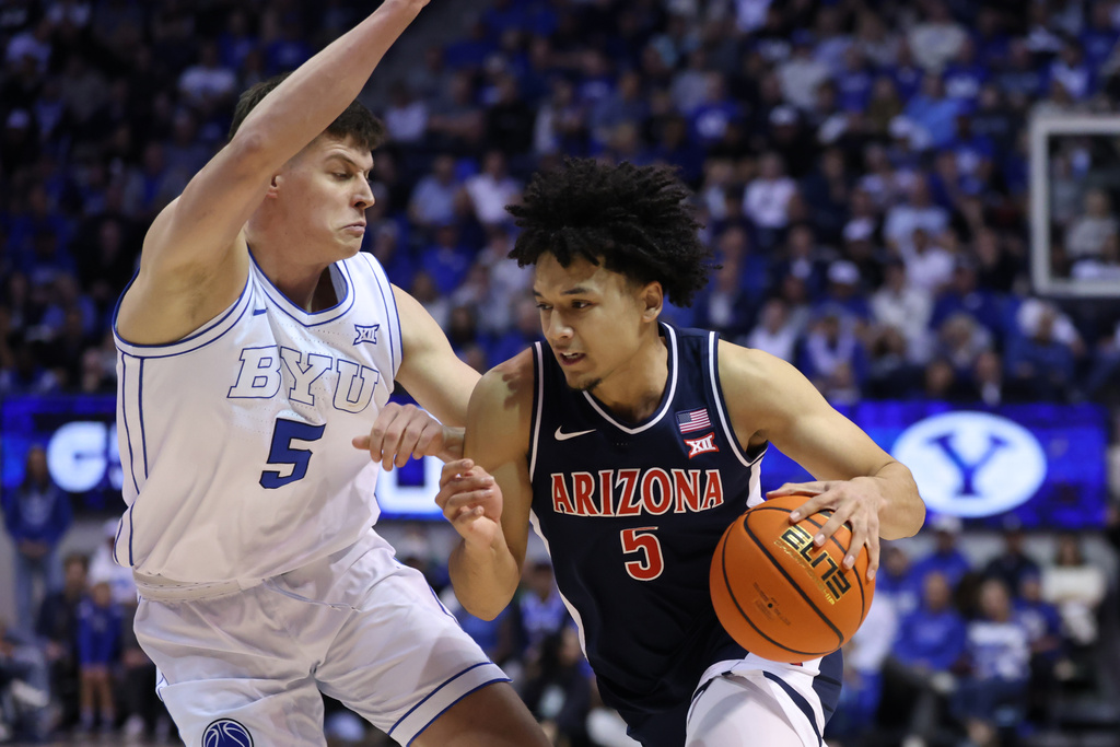 Arizona guard Brayden Burries, right, moves the ball as BYU forward Mihailo Boskovic (5) defends during the second half of an NCAA college basketball game, Monday, Jan. 26, 2026, in Provo, Utah. (AP Photo/Rob Gray)