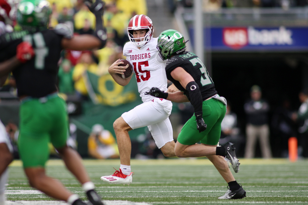 Indiana quarterback Fernando Mendoza (15) runs the ball while defended by Oregon defensive back Dillon Thieneman, right, during the first half of an NCAA college football game, Saturday, Oct. 11, 2025, in Eugene, Ore. (AP Photo/Lydia Ely)