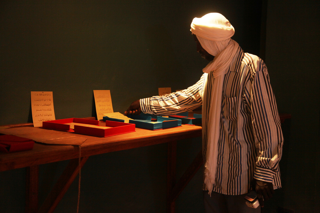 An employee of the Ahmed Baba Institute of Higher Islamic Studies and Research displays manuscripts at the exhibition hall in Timbuktu, Mali, Sept. 4, 2025. (AP Photo/Baba Ahmed)