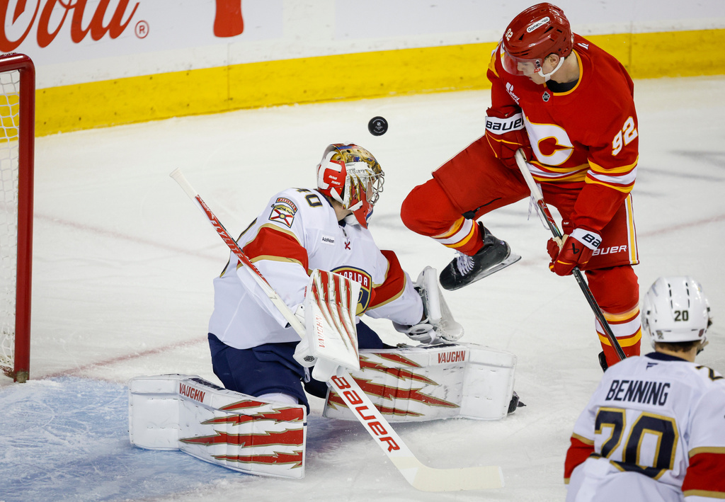 Florida Panthers goalie Daniil Tarasov, left, blocks the net against Calgary Flames' Matvei Gridin, top right, during first-period NHL hockey game action in Calgary, Alberta, Friday, March 20, 2026. (Jeff McIntosh/The Canadian Press via AP)