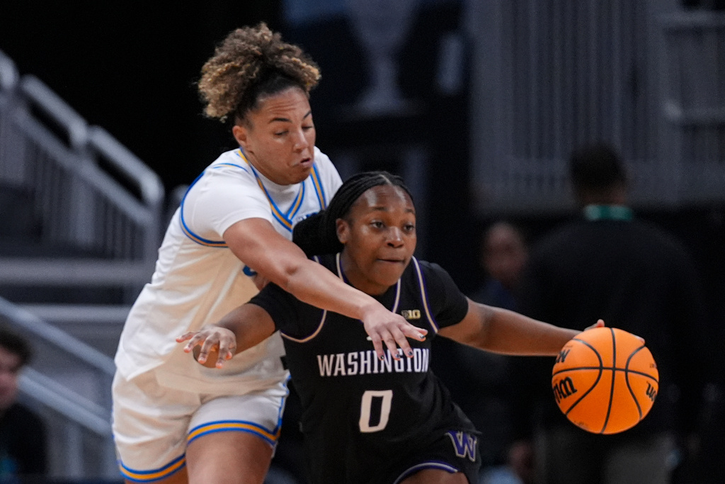 UCLA guard Kiki Rice (1) reaches over Washington guard Sayvia Sellers (0) in the first half of an NCAA college basketball game in the quarterfinals of the Big Ten Conference tournament, Friday, March 6, 2026 in Indianapolis. (AP Photo/Michael Conroy)