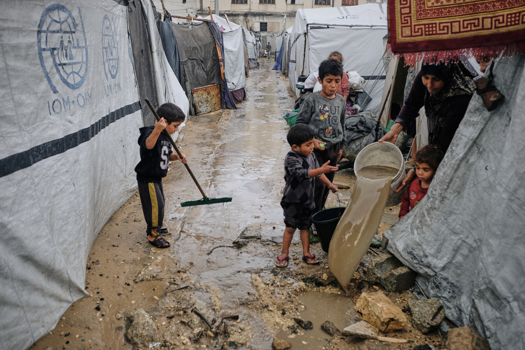 Displaced Palestinians clear water from their flooded tent at a temporary camp after heavy rainfall in Gaza City Tuesday, Nov. 25, 2025. (AP Photo/Jehad Alshrafi)