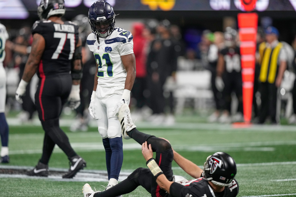 Seattle Seahawks cornerback Devon Witherspoon looks down at Atlanta Falcons quarterback Kirk Cousins after a tackle during the first half of an NFL football game, Sunday, Dec. 7, 2025, in Atlanta. (AP Photo/Brynn Anderson)