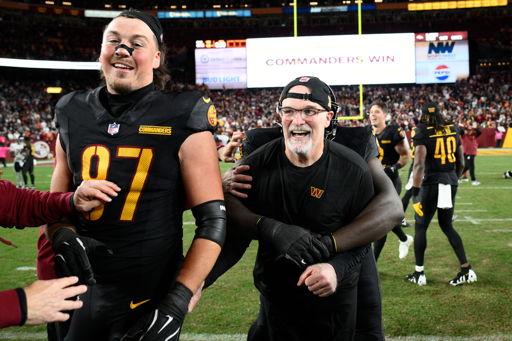 FILE - Washington Commanders head coach Dan Quinn and tight end John Bates (87) celebrate after the Commanders beat the Chicago Bears 18-15 in an NFL football game, Oct. 27, 2024, in Landover, Md. (AP Photo/Nick Wass, File)