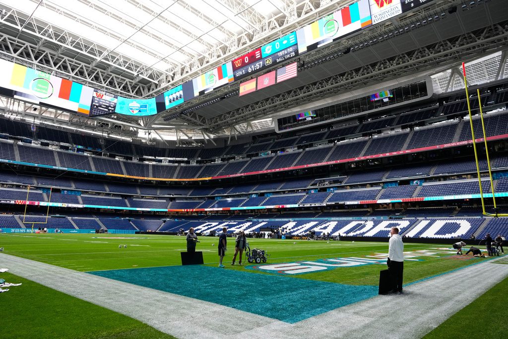 Workers prepare the field at the Santiago Bernabeu stadium ahead of an NFL game between the Miami Dolphins and Washington Commanders in Madrid, Spain, Friday, Nov. 14, 2025. (AP Photo/Steve Luciano)