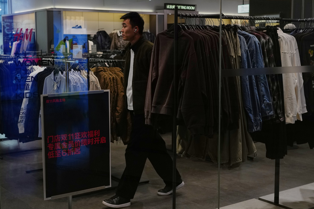 A man shops at a Sweden-based clothing company H&M displaying a poster to promote Singles' Day discounts for membership at a shopping mall in Beijing on Nov. 10, 2025. (AP Photo/Andy Wong)