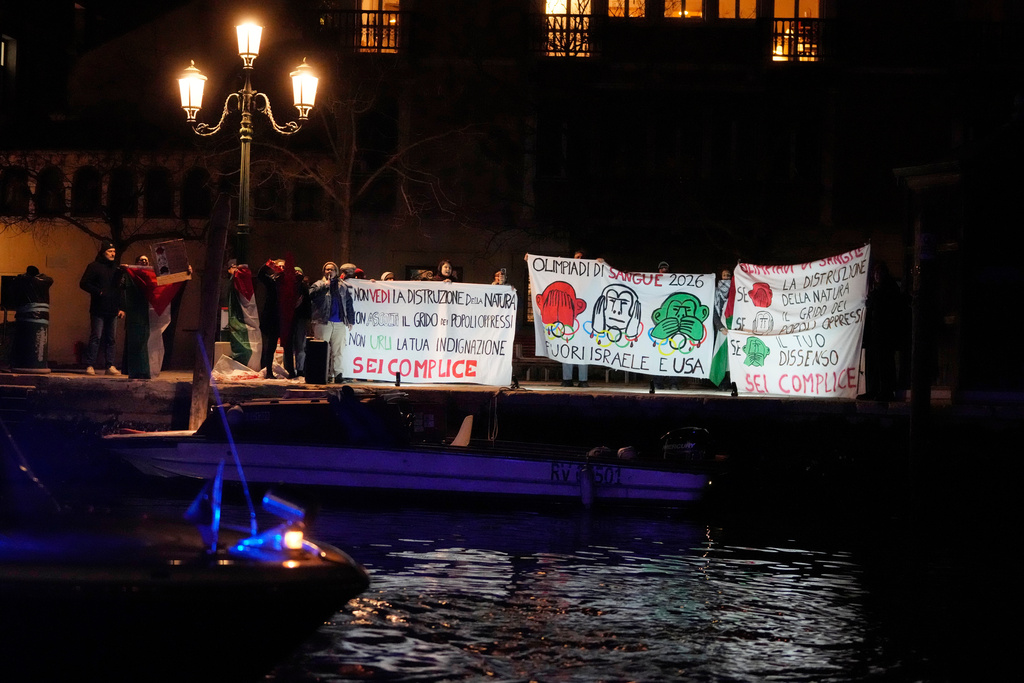 A small group of anti-war activists protest the participation of Israel and the US in the Milan Cortina Olympic Games as the Olympic flame glides down the Grand Canal in Venice, Italy, its journey will conclude in Milan on February 6 for the Winter Olympics opening ceremony. (AP Photo/Luca Bruno)