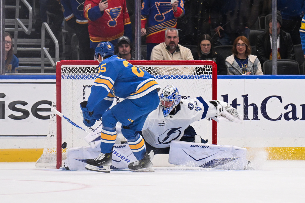 St. Louis Blues' Jordan Kyrou, left, scores the winning goal past Tampa Bay Lightning goaltender Andrei Vasilevskiy, right, in a shootout during an NHL hockey game Friday, Jan. 16, 2026, in St. Louis. (AP Photo/Connor Hamilton)