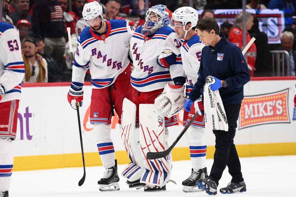 New York Rangers goaltender Igor Shesterkin, third from right, is helped to the bench after he was injured during the second period of an NHL hockey game against the Washington Capitals, Friday, Oct. 9, 2026, in Washington. (AP Photo/Nick Wass)