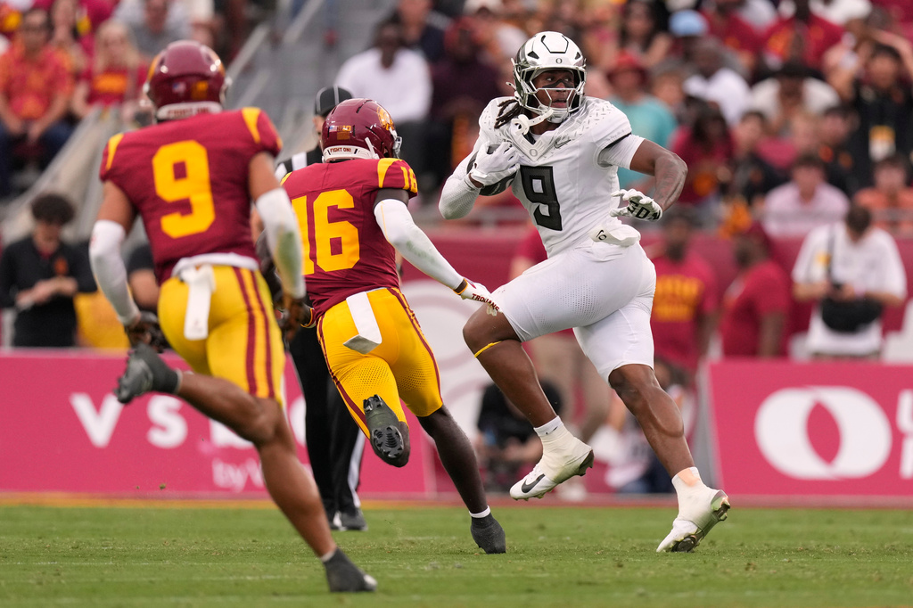 Oregon tight end Jamari Johnson, right, runs the ball as Southern California safety Kennedy Urlacher, left, and safety Prophet Brown defend during the first half of an NCAA college football game, Saturday, Sept. 26, 2026, in Los Angeles. (AP Photo/Mark J. Terrill)