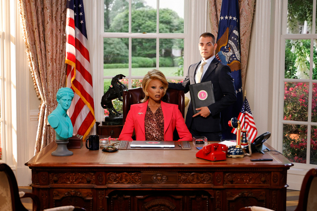 RuPaul, seated, and Matt Rogers appear in a scene from "Stop! That! Train!" (Bleecker Street and World of Wonder via AP)