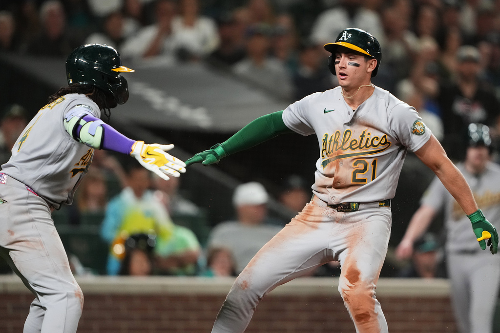 Athletics' Tyler Soderstrom (21) greets teammate Lawrence Butler, left, after scoring on a sacrifice fly from Max Muncy against the Seattle Mariners during the eighth inning of a baseball game, Monday, April 20, 2026, in Seattle. (AP Photo/Lindsey Wasson)