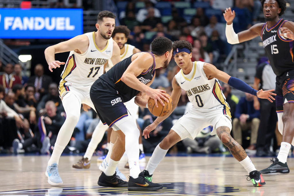 Phoenix Suns guard Devin Booker, center, tries to make a move against New Orleans Pelicans forward Karlo Matkovic (17) and guard Jeremiah Fears (0) in the first half of an NBA basketball game Friday, Dec. 26, 2025, in New Orleans. (AP Photo/Peter Forest)