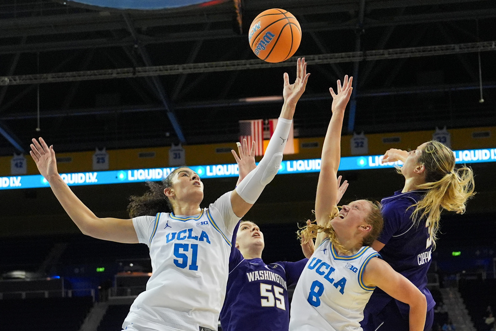 UCLA center Lauren Betts (51) and guard Gianna Kneepkens (8) reach for a rebound against Washington center Yulia Grabovskaia (55) and guard Devin Coppinger (3) during the first half of an NCAA women's college basketball game in Los Angeles, Thursday, Feb. 19, 2026. (AP Photo/Jae C. Hong)