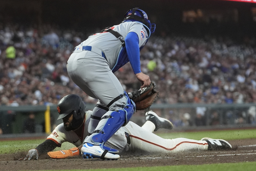 San Francisco Giants' Heliot Ramos, bottom, slides home to score under Chicago Cubs catcher Carson Kelly during the third inning of a baseball game in San Francisco, Wednesday, Aug. 27, 2025. (AP Photo/Jeff Chiu)