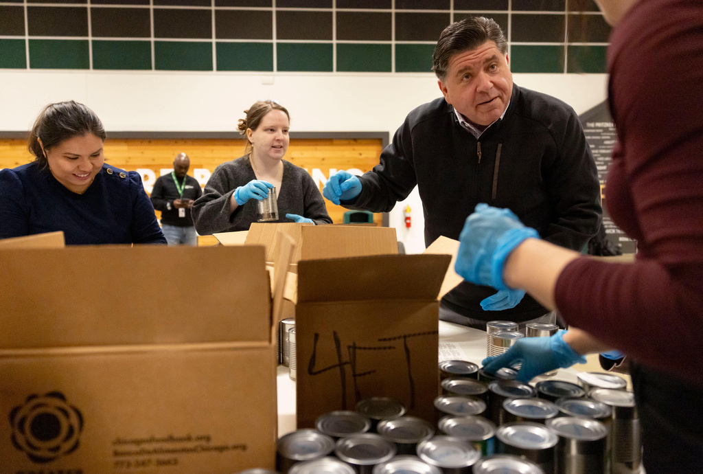 Gov. JB Pritzker packs boxes of canned goods with members of his staff while volunteering Thursday, Dec. 4, 2025, at the Greater Chicago Food Depository. (Brian Cassellav /Chicago Tribune via AP, Pool)