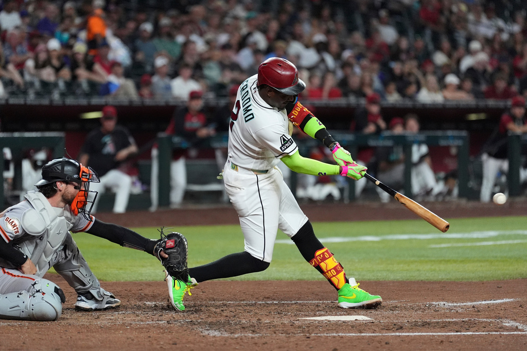 Arizona Diamondbacks' Geraldo Perdomo, right, connects for a 3-run double as San Francisco Giants catcher Eric Haase reaches for the ball during the fifth inning of a baseball game, Monday, June 29, 2026, in Phoenix. (AP Photo/Ross D. Franklin)