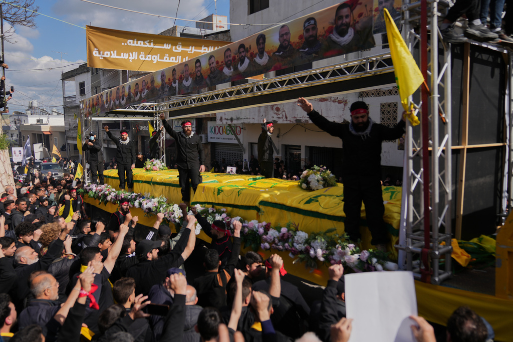 Coffins of Hezbollah fighters killed before the ceasefire in the war between Hezbollah and Israel are carried on a truck past mourners during a mass funeral procession in the southern village of Kfar Sir, Lebanon, Tuesday, April 21, 2026. (AP Photo/Hassan Ammar)