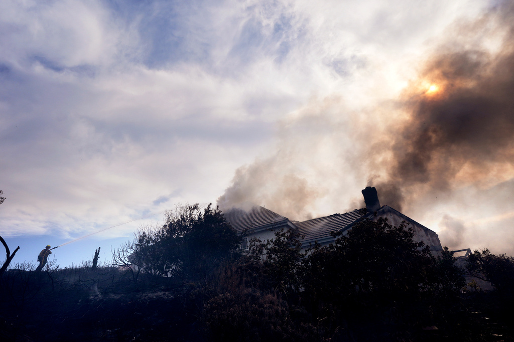 A firefighters works to put out a fire on a house engulfed in flames during the Norte Fire on Friday, Oct. 16, 2026, in San Juan Capistrano, Calif. (AP Photo/Jae C. Hong)