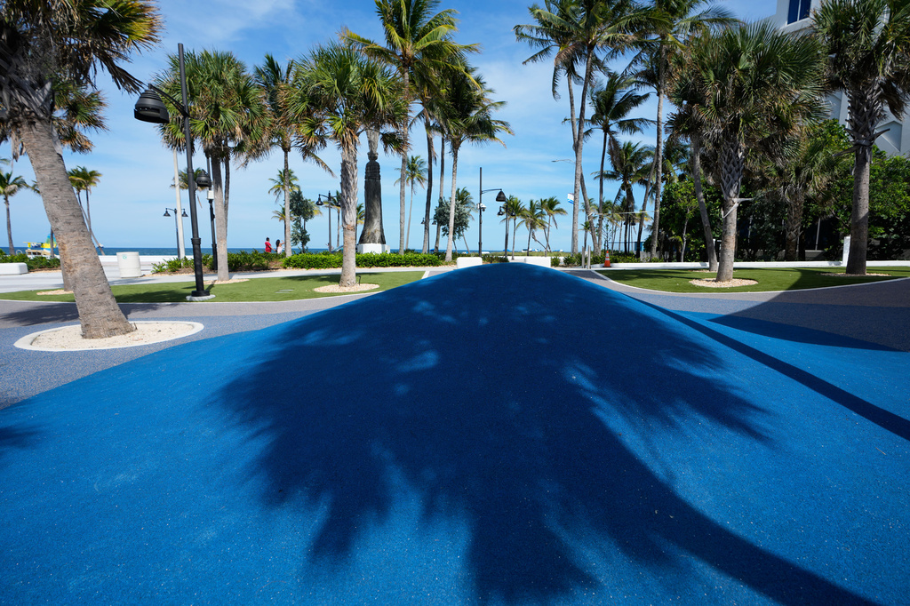 A shadow of a palm tree is cast on a playscape at DC Alexander Park, a former parking lot that was transformed into a public space that doubles as flood infrastructure, Tuesday, June 30, 2026, in Fort Lauderdale, Fla. (AP Photo/Lynne Sladky)