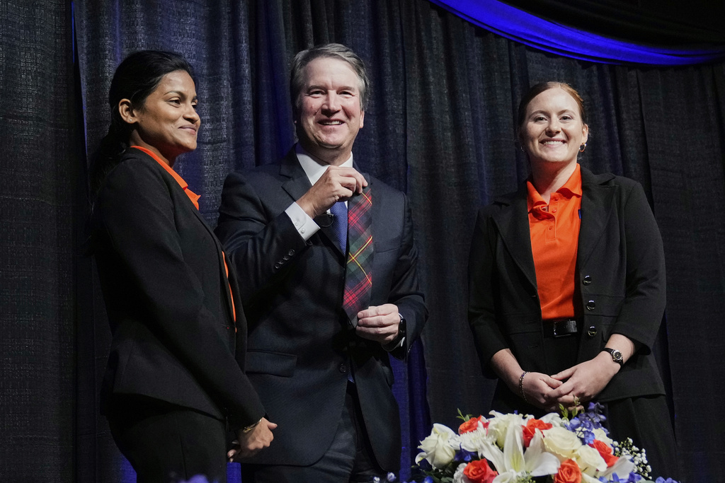 Justice Brett Kavanaugh, center, holds up a gift he was presented by McLennan Community honors college student liason's Vino Dean, left, and Brenna Rollins, right, after Kavanaugh spoke at The Ken Starr Lecture at the college, Thursday, Sept. 11, 2025, in Waco, Texas. (AP Photo/Tony Gutierrez)