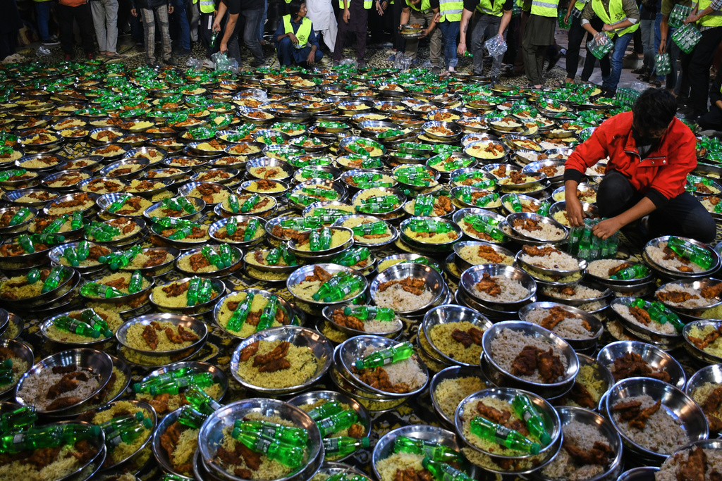 A volunteer prepares food plates which will be distributed among families for pre-dawn meal or 'Sehri' to start their fasting during the Muslim's holy fasting month of Ramadan, at a free meal distribution center run by a charity group, in Karachi, Pakistan, Thursday, Feb. 19, 2026. (AP Photo/Ali Raza)