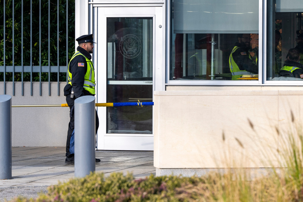A US guard walks with the Ukrainian flag in front of the US Permanent Mission, in Geneva, Switzerland, Sunday, Nov. 23, 2025. (Martial Trezzini/Keystone via AP)