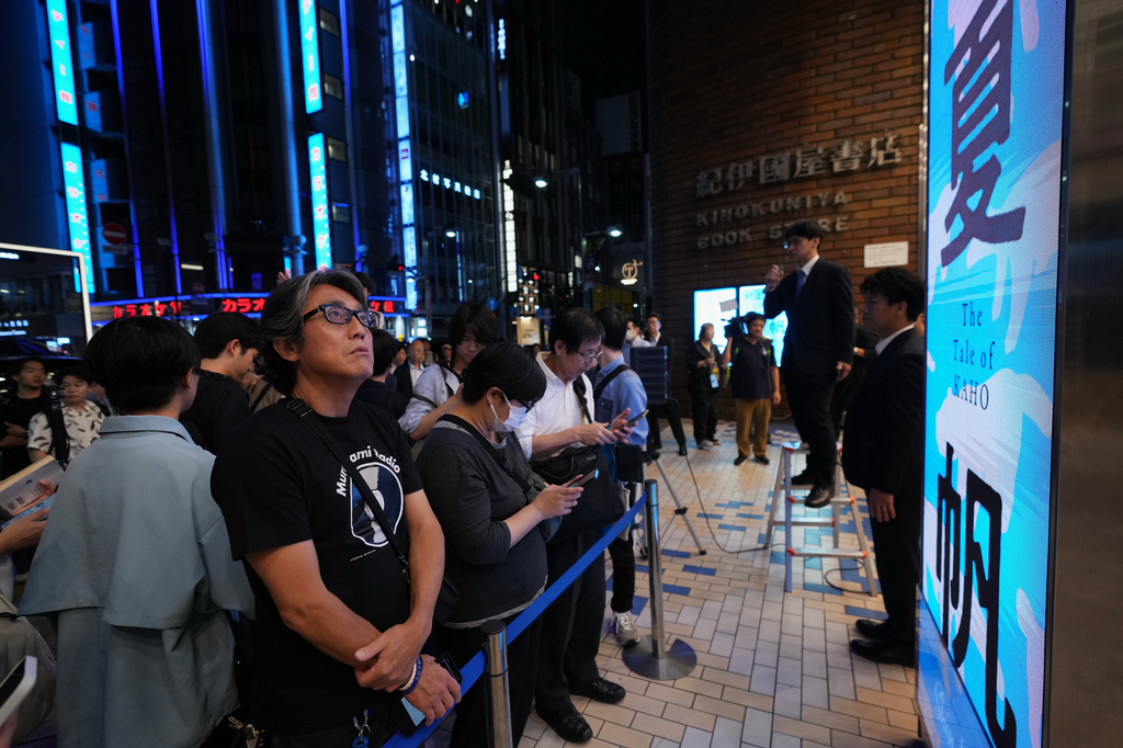 People attend a countdown event to receive copies they pre-purchased, of Haruki Murakami's new book, titled "The Tale of KAHO" after the clock strikes midnight, at a Kinokuniya bookstore in Tokyo on Thursday, July 2, 2026. (AP Photo/Hiro Komae)