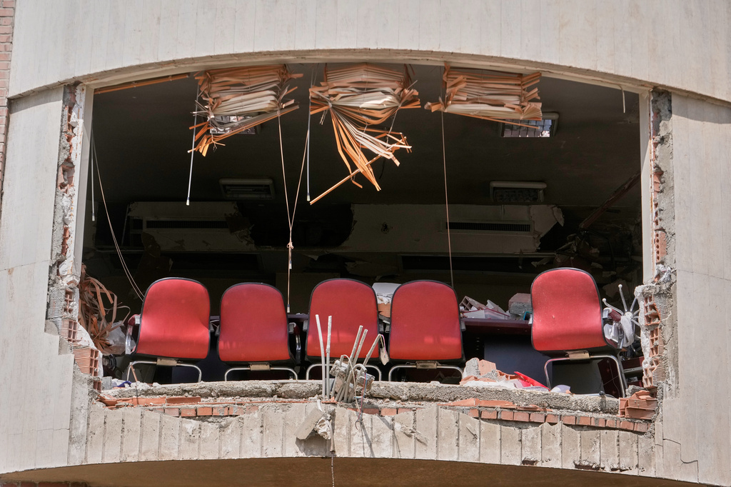 A row of chairs is seen through a hole left by U.S.-Israeli airstrikes Friday at Shahid Beheshti University in Tehran, Iran, Saturday, April 4, 2026. (AP Photo/Vahid Salemi)