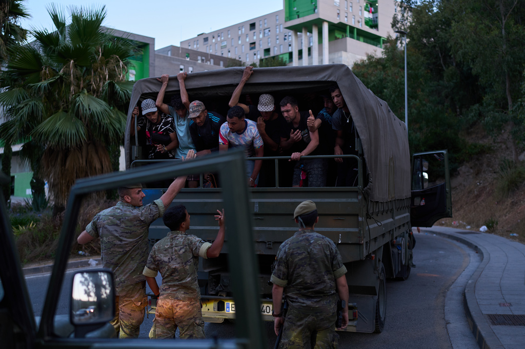 Migrants who crossed into Spain are escorted by Spanish soldiers towards the Spanish-Moroccan border for their return to Morocco from the Spanish enclave of Ceuta, Sunday, Aug. 2, 2026. (AP Photo/Bernat Armangue)