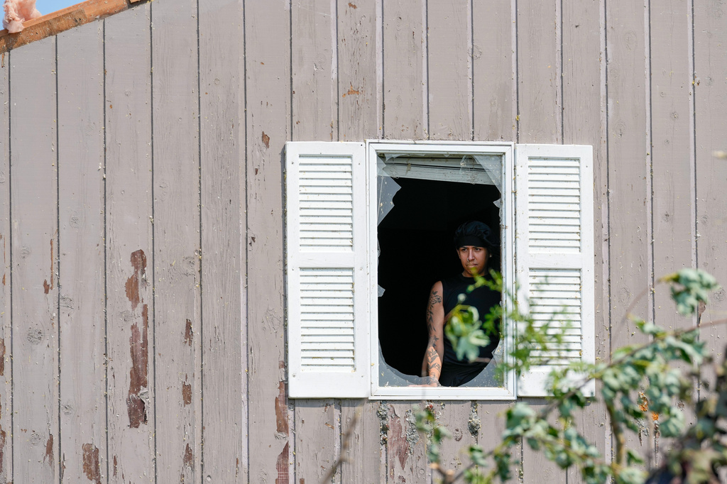 Alex Leon looks through a broken window after a tornado hit the day before, Tuesday, July 28, 2026, in Menasha, Wis. (AP Photo/Kayla Wolf)
